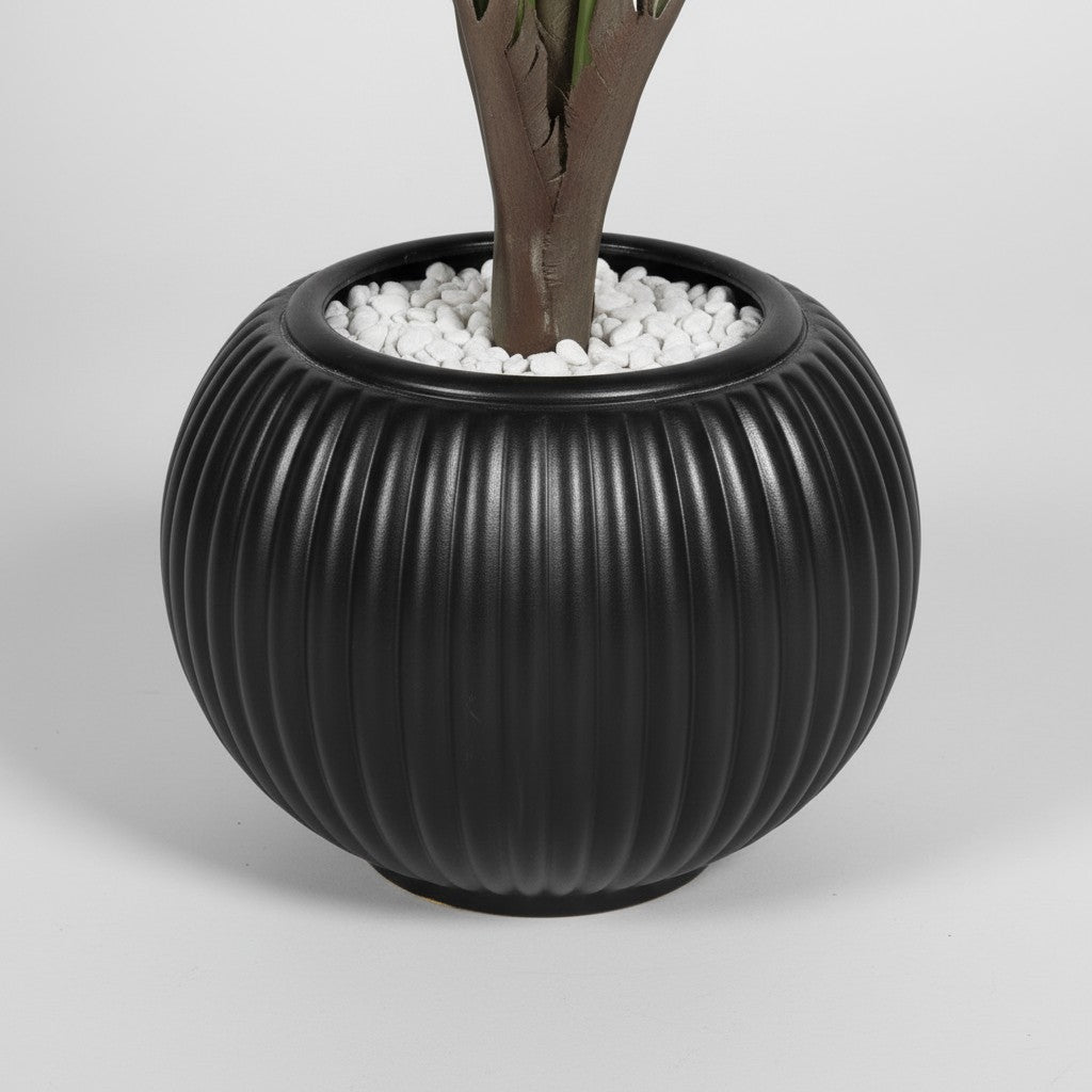 Wadi Home artificial fan palm plant in a round ribbed black ceramic-style planter topped with white decorative stones.