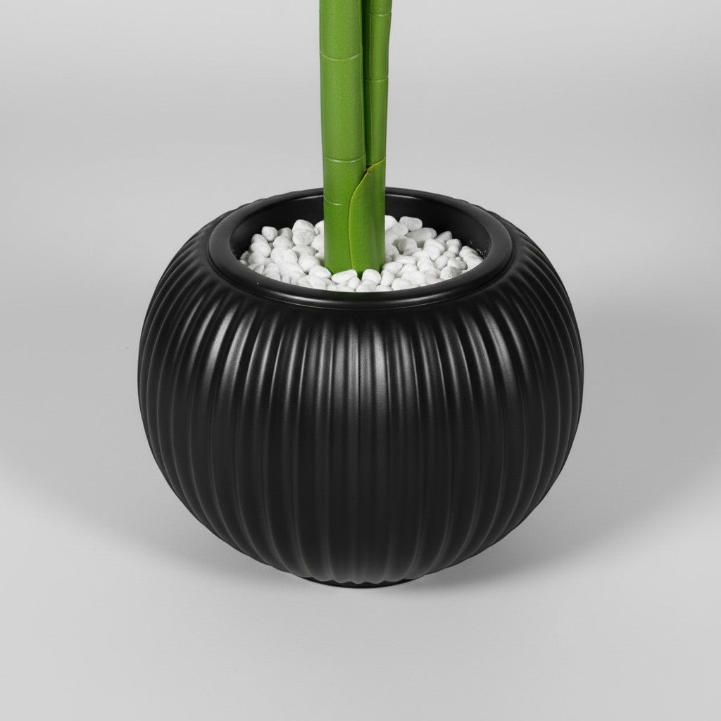 Wadi Home artificial plant in a round ribbed black pot with decorative white stones at the base