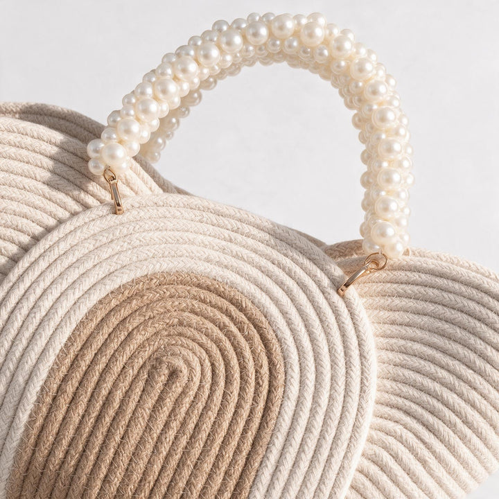 Wadi Home beige braided rope handbag featuring a decorative pearl-beaded handle for an elegant summer style.