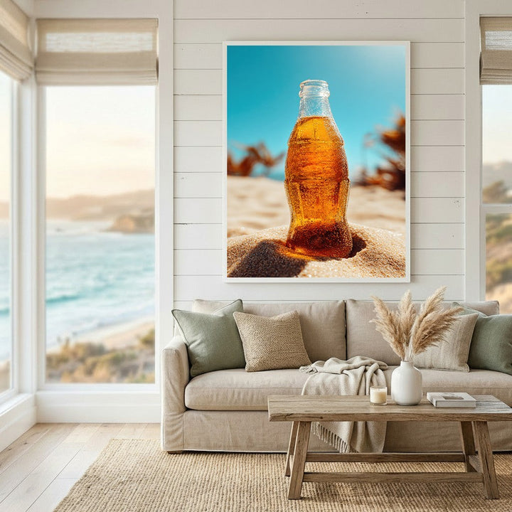 Wadi Home summer beverage wall art print featuring a cold glass bottle on beach sand, displayed in a coastal living room