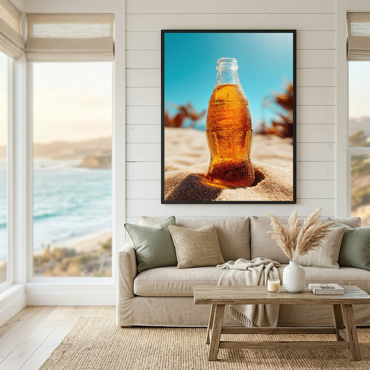 Wadi Home framed wall art of a condensation-covered glass bottle in beach sand against a bright blue sky in a living room