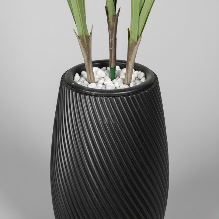 Wadi Home artificial plant in a black textured spiral vase with white decorative stones at the base