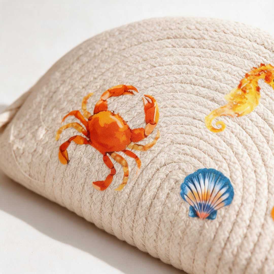 Wadi Home beige woven half moon clutch bag featuring colorful crab, seahorse, and seashell beach-themed prints.
