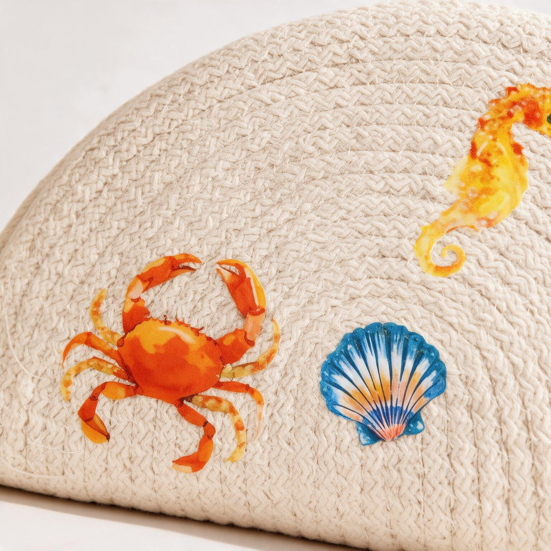 Wadi Home beige woven half moon clutch bag featuring colorful crab, seahorse, and seashell beach-themed prints.
