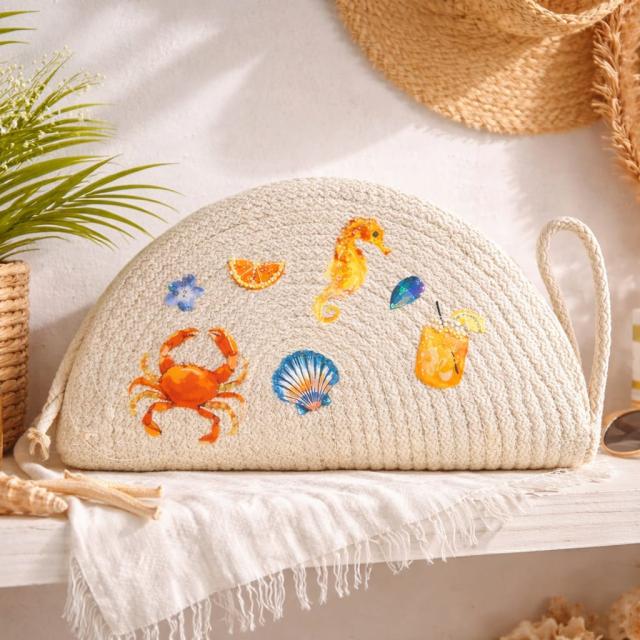 Wadi Home beige woven half moon clutch bag featuring colorful beach-themed prints of a crab, seahorse, and drinks.