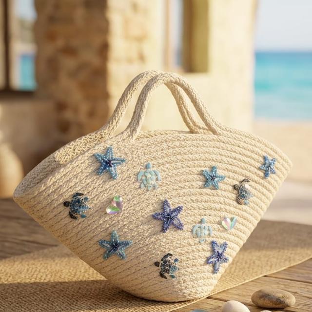 Wadi Home off-white woven rope beach tote with blue starfish and sea turtle embellishments on a coastal patio
