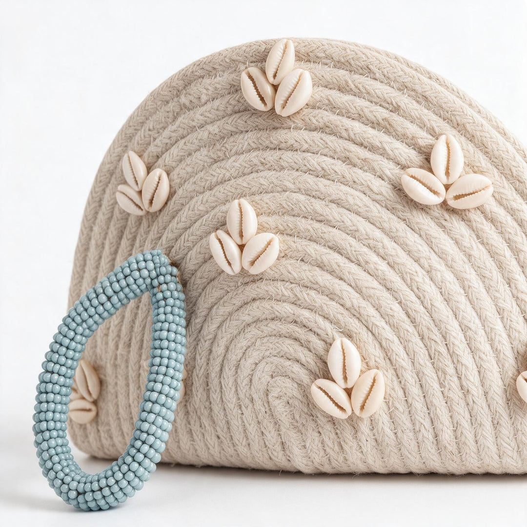 Wadi Home handwoven beige rope half moon clutch bag decorated with cowrie shells and a light blue beaded handle