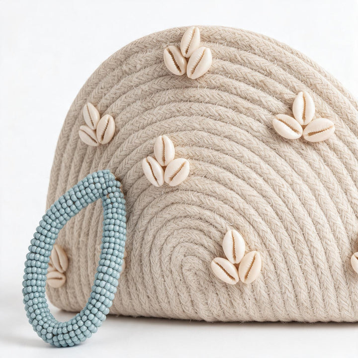 Wadi Home handwoven beige rope half moon clutch bag decorated with cowrie shells and a light blue beaded handle