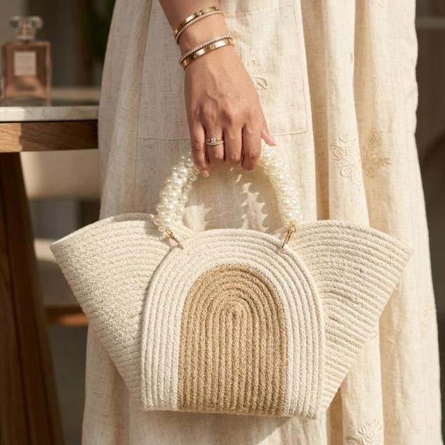 Wadi Home beige braided rope handbag with a chic pearl-beaded handle, held by a woman in a linen dress.