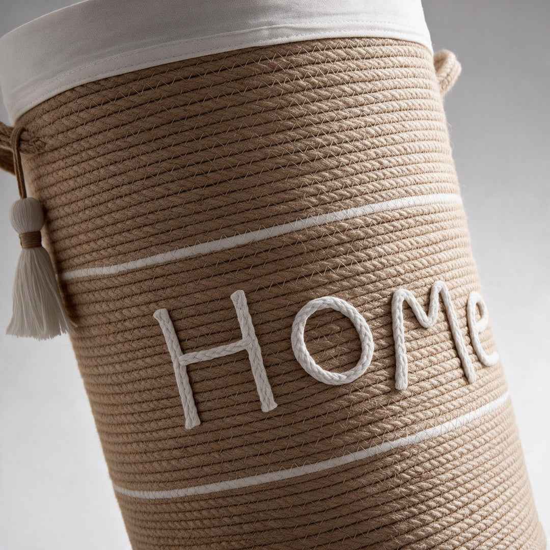 Wadi Home woven rope laundry hamper in beige with white Home text, lid, and decorative tassel detail.