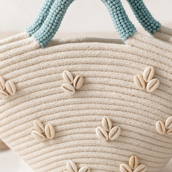 Wadi Home beige woven beach handbag featuring white shell embellishments and textured light blue beaded handles