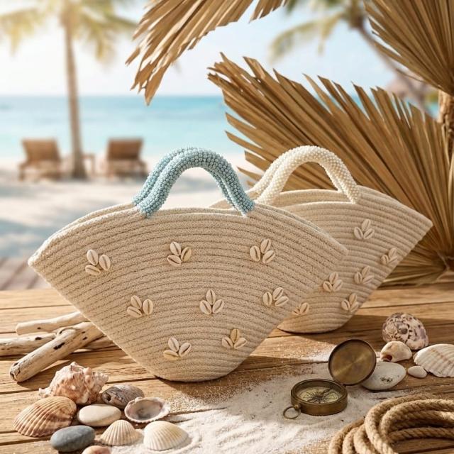 Wadi Home beige woven semi-circular beach handbags with shell embellishments and blue or white handles on a sandy table