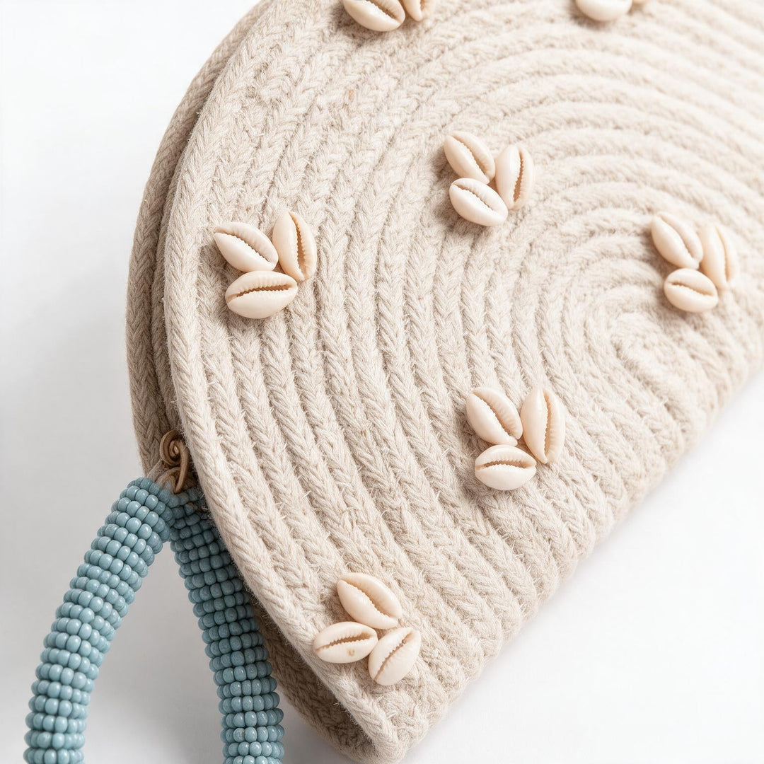 Wadi Home handwoven beige rope half moon clutch bag decorated with cowrie shells and a blue beaded handle