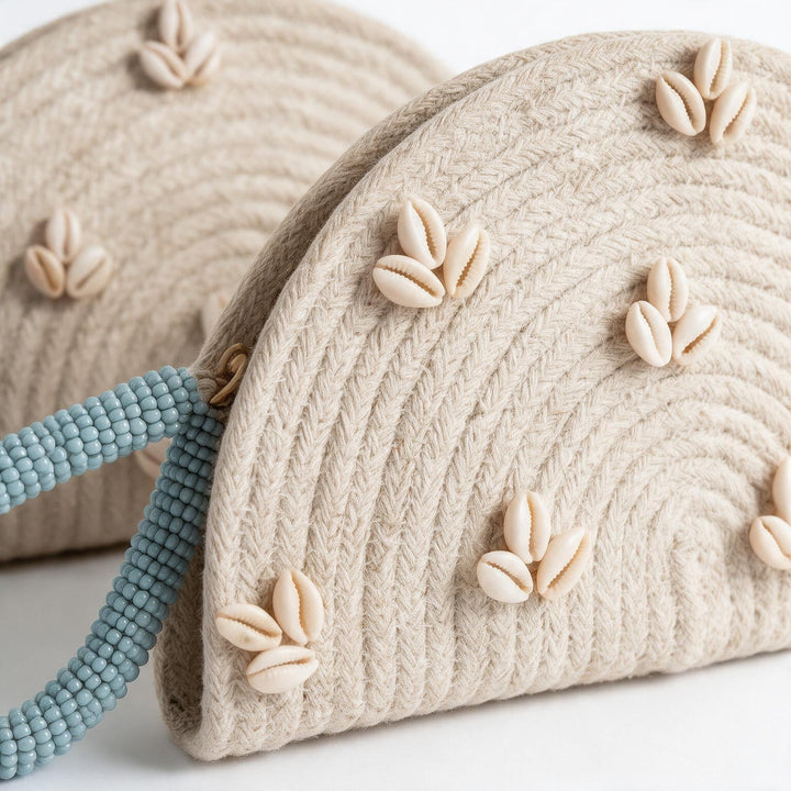 Wadi Home handwoven beige rope half moon clutch bag decorated with cowrie shells and a blue beaded handle