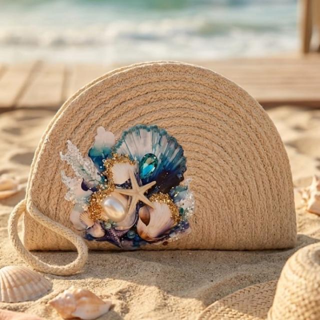 Wadi Home beige woven straw beach clutch decorated with seashells, a starfish, pearls, and blue ocean-themed accents.