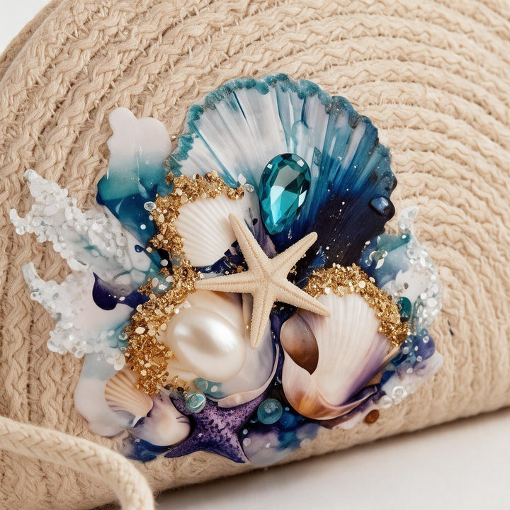 Wadi Home beige woven straw beach clutch featuring seashells, a starfish, pearls, and blue ocean-inspired accents.