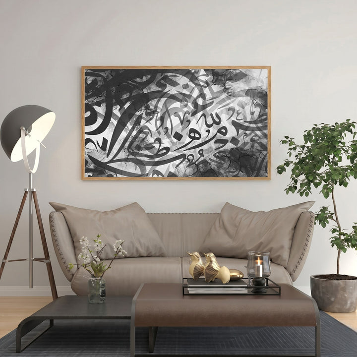 Wadi Home abstract Arabic calligraphy wall art in monochrome, framed in light wood, displayed above a sofa.