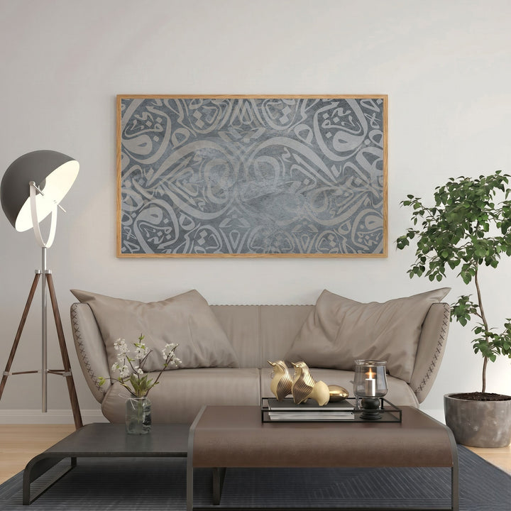 Wadi Home abstract Arabic calligraphy art in grey tones, framed in natural wood, displayed above a sofa.