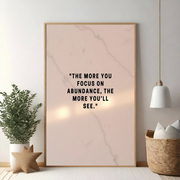 Wadi Home inspirational wall art with black text on a soft pink marble background: "The more you focus on abundance, the more you'll see."