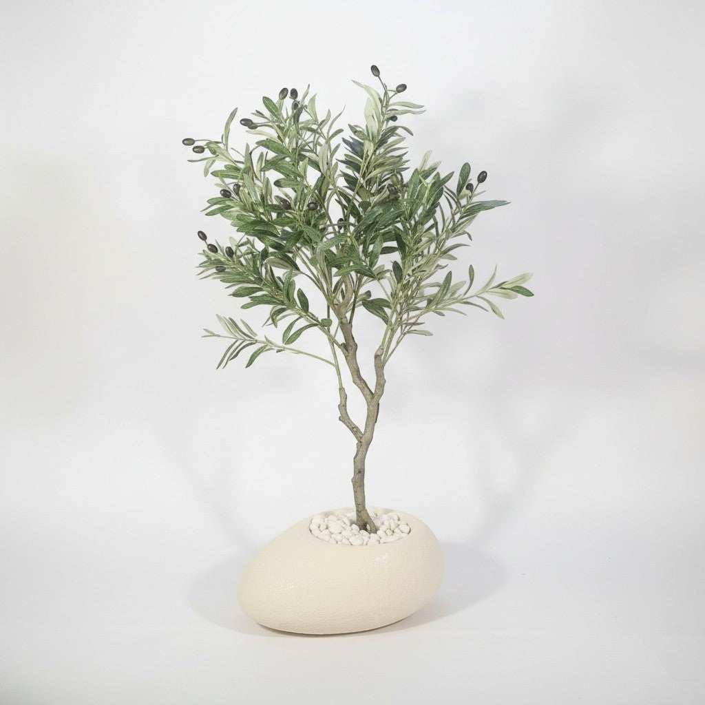 Wadi Home artificial olive tree with green leaves and dark olives in a cream stone-effect planter with white pebbles.