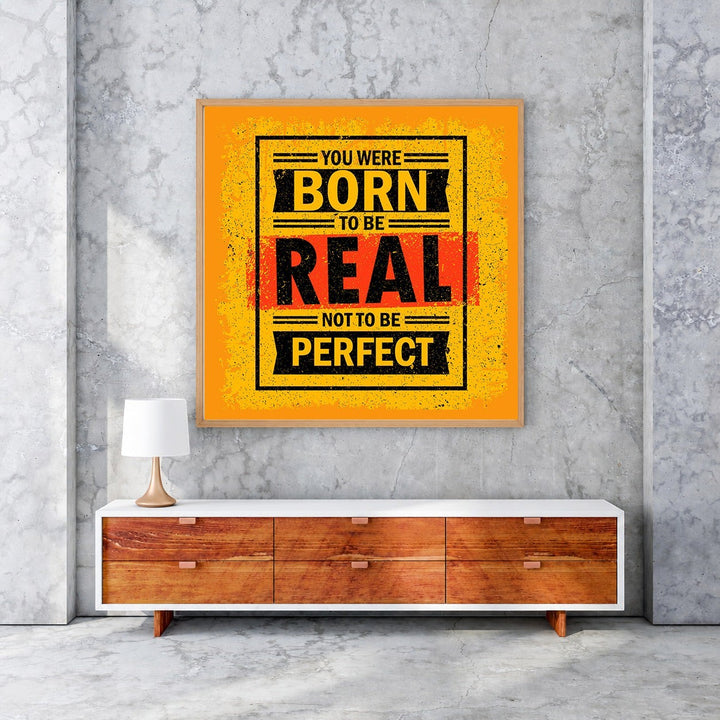 Wadi Home motivational wall art with bold yellow, black, and red typography reading 'You Were Born To Be Real, Not To Be Perfect'.