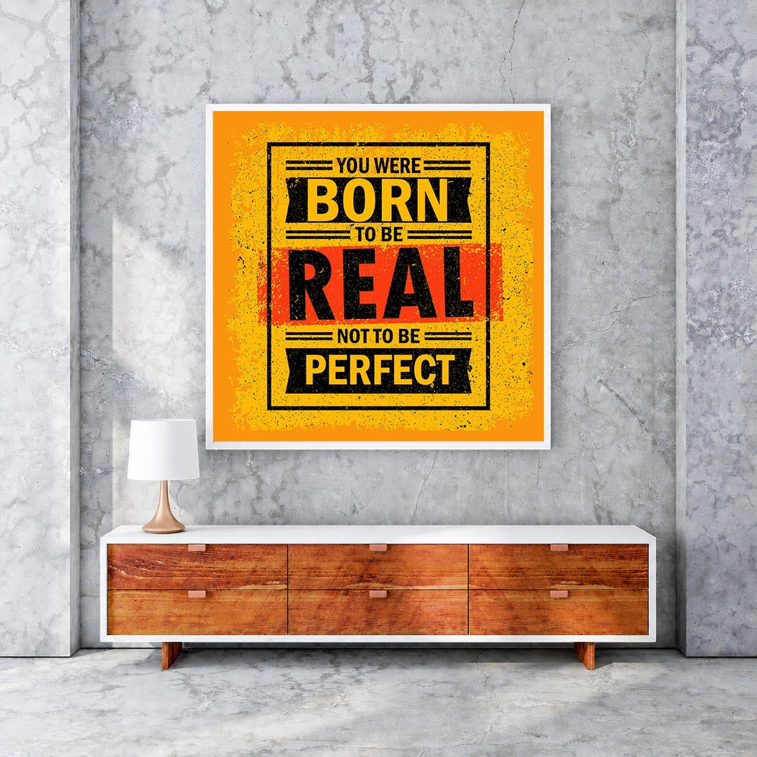 Wadi Home motivational wall art with bold yellow, black, and red typography reading 'You Were Born To Be Real Not To Be Perfect'.