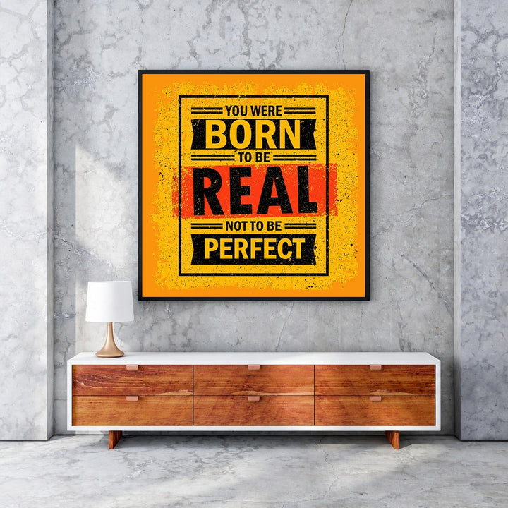 Wadi Home motivational wall art with bold yellow, black, and red typography reading 'You Were Born To Be Real Not To Be Perfect'.