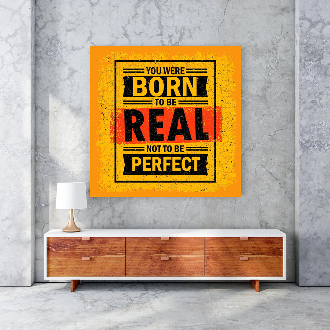 Wadi Home motivational wall art with bold yellow, black, and red typography reading 'You Were Born To Be Real Not To Be Perfect'.