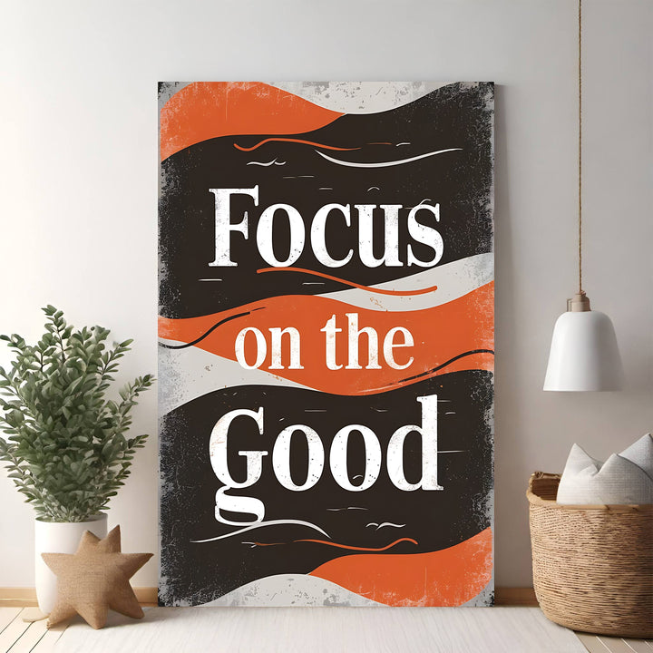 Wadi Home motivational wall art with bold white typography reading "Focus on the Good" against a distressed black, orange, and grey background.
