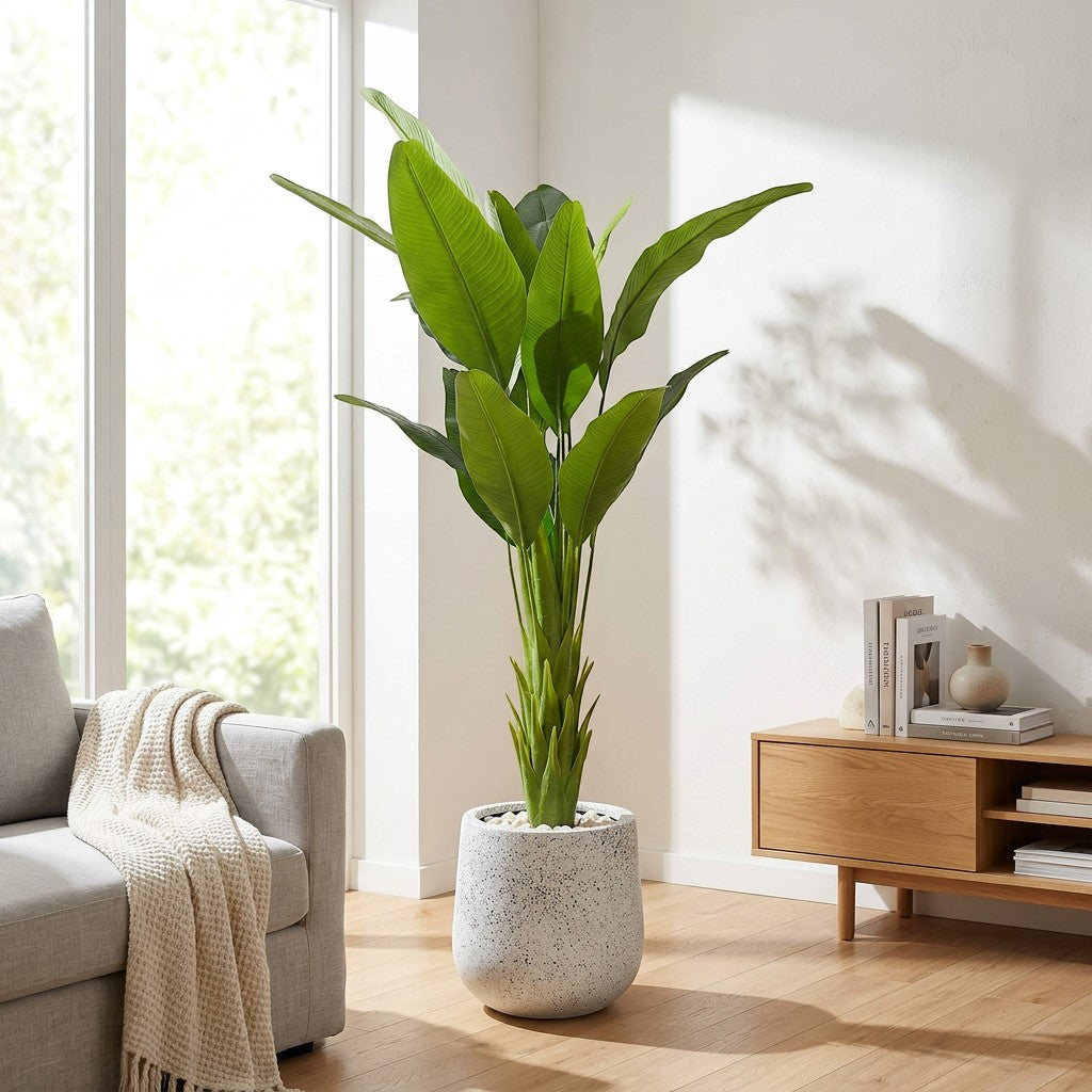 Wadi Home Large Faux Bird of Paradise Plant with lush green leaves in a speckled grey pot, placed in a modern living room.