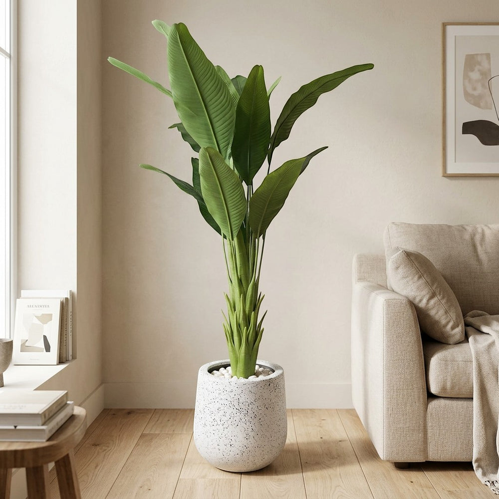 Wadi Home Large Faux Bird of Paradise Plant with lush green leaves in a speckled white pot, placed indoors.