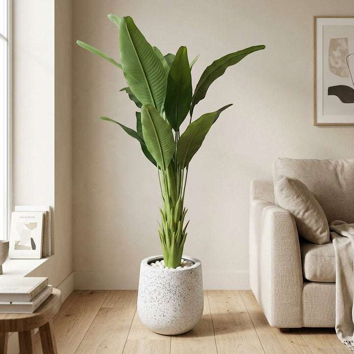 Wadi Home Large Faux Bird of Paradise Plant with lush green leaves in a speckled white pot, placed indoors.