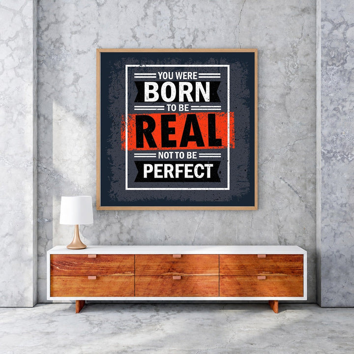 Wadi Home motivational wall art with bold typography: "You Were Born To Be Real Not To Be Perfect" in black, white, and orange.