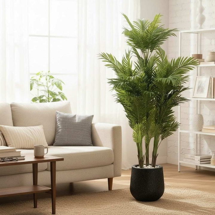 Wadi Home Tall Faux Areca Palm Tree with lush green fronds in a black speckled planter, adds tropical ambiance to living room.