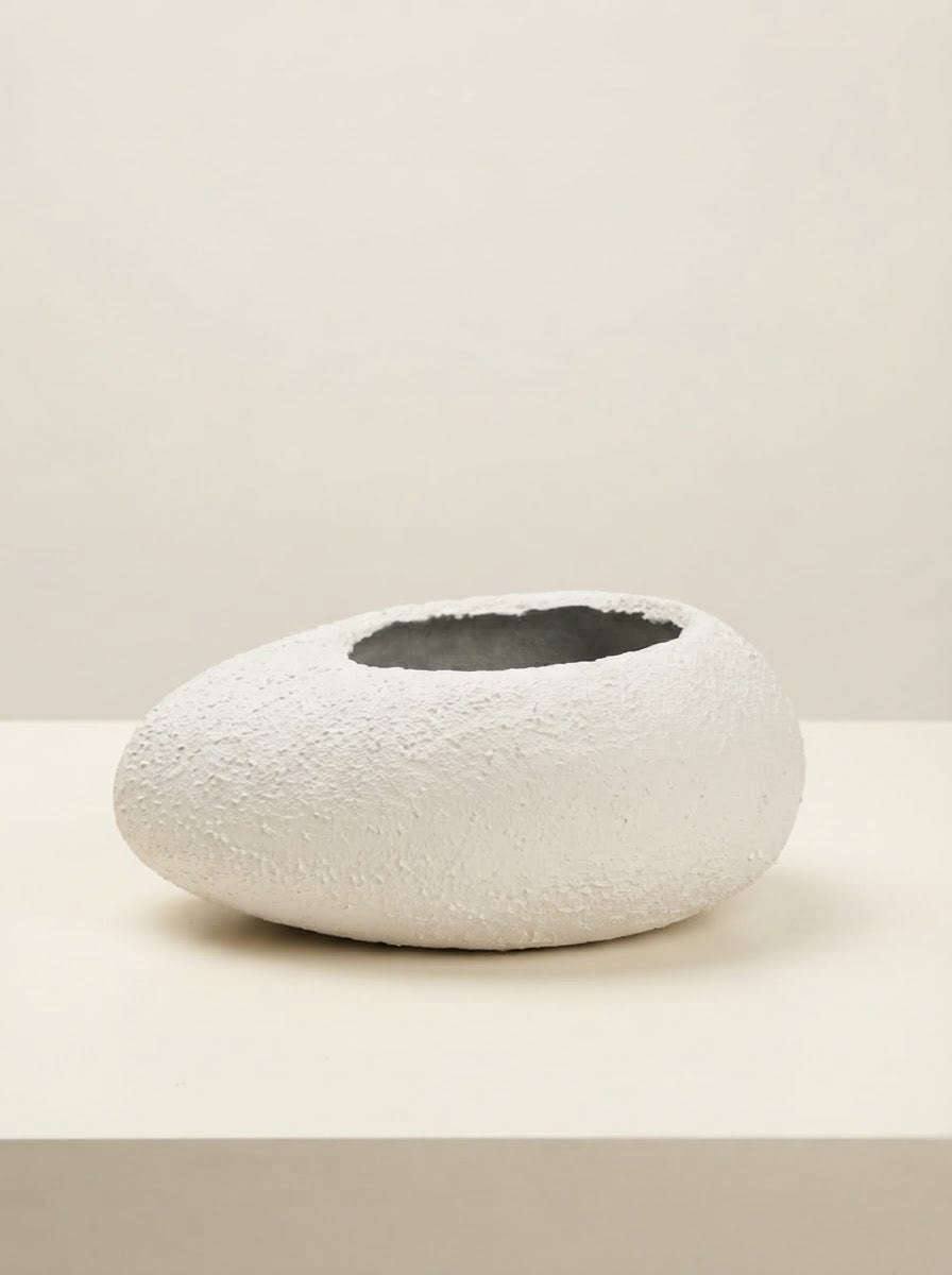 Low wide white textured fiberglass bowl planter with a circular opening resting on a cream tabletop against a plain neutral background.