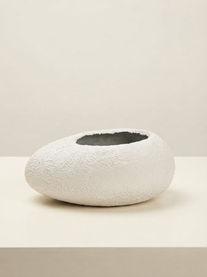 Low wide white textured fiberglass bowl planter with a circular opening resting on a cream tabletop against a plain neutral background.