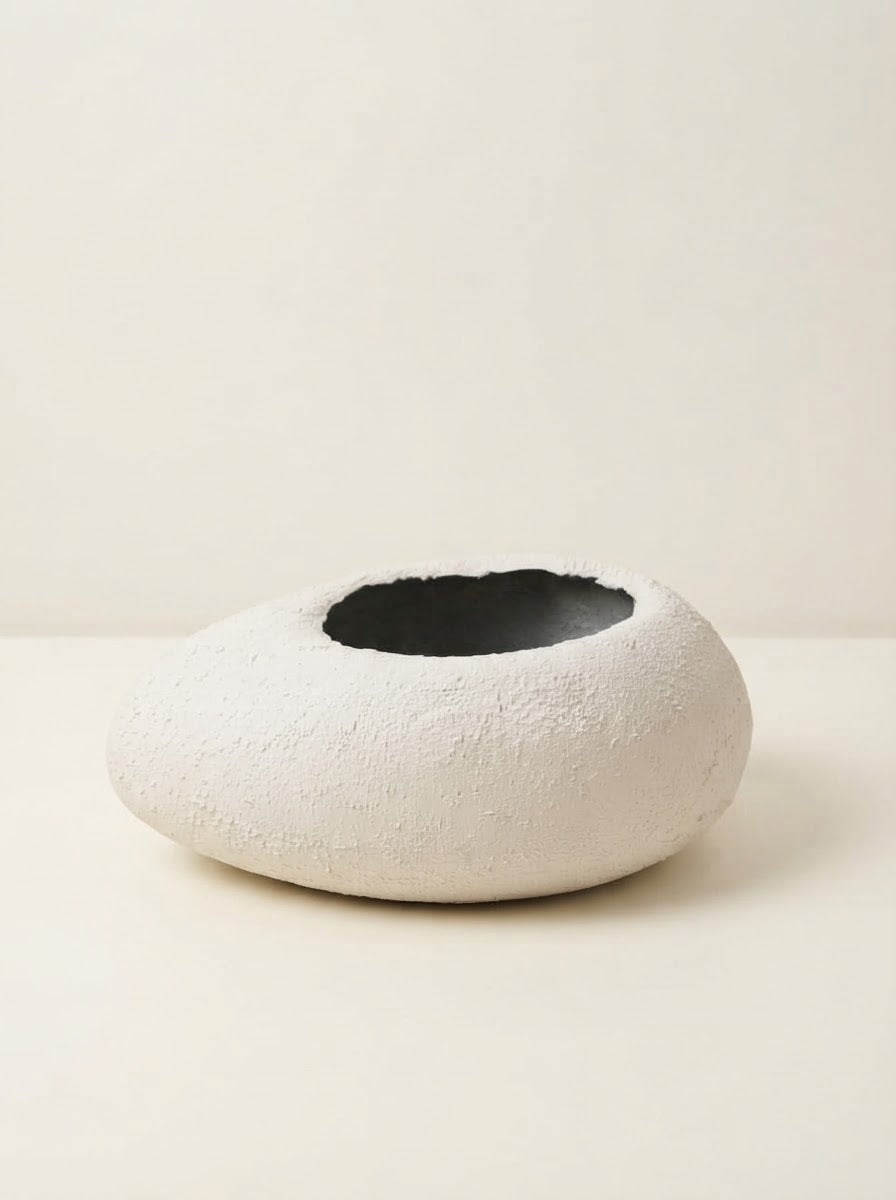 Low wide white textured fiberglass bowl planter with a circular opening resting on a cream tabletop against a plain neutral background.