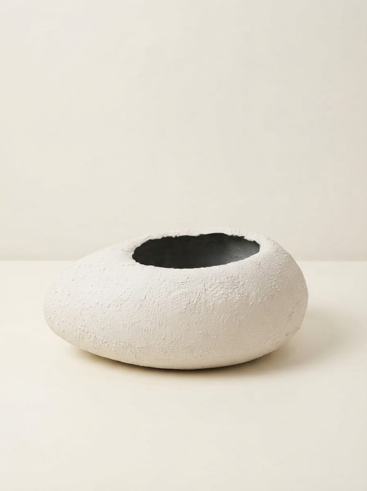 Low wide white textured fiberglass bowl planter with a circular opening resting on a cream tabletop against a plain neutral background.