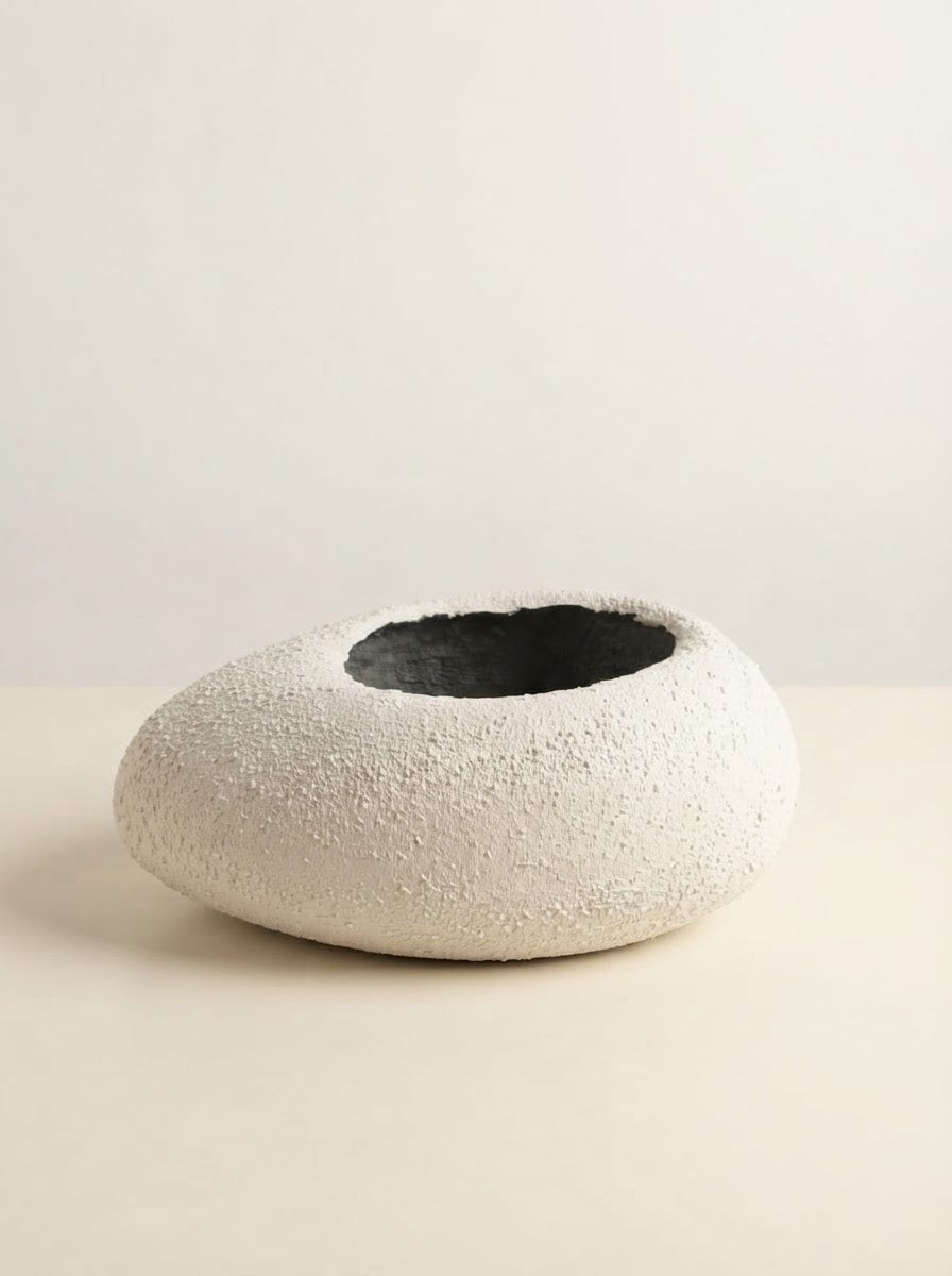 Low wide white textured fiberglass bowl planter with a circular opening resting on a cream tabletop against a plain neutral background.